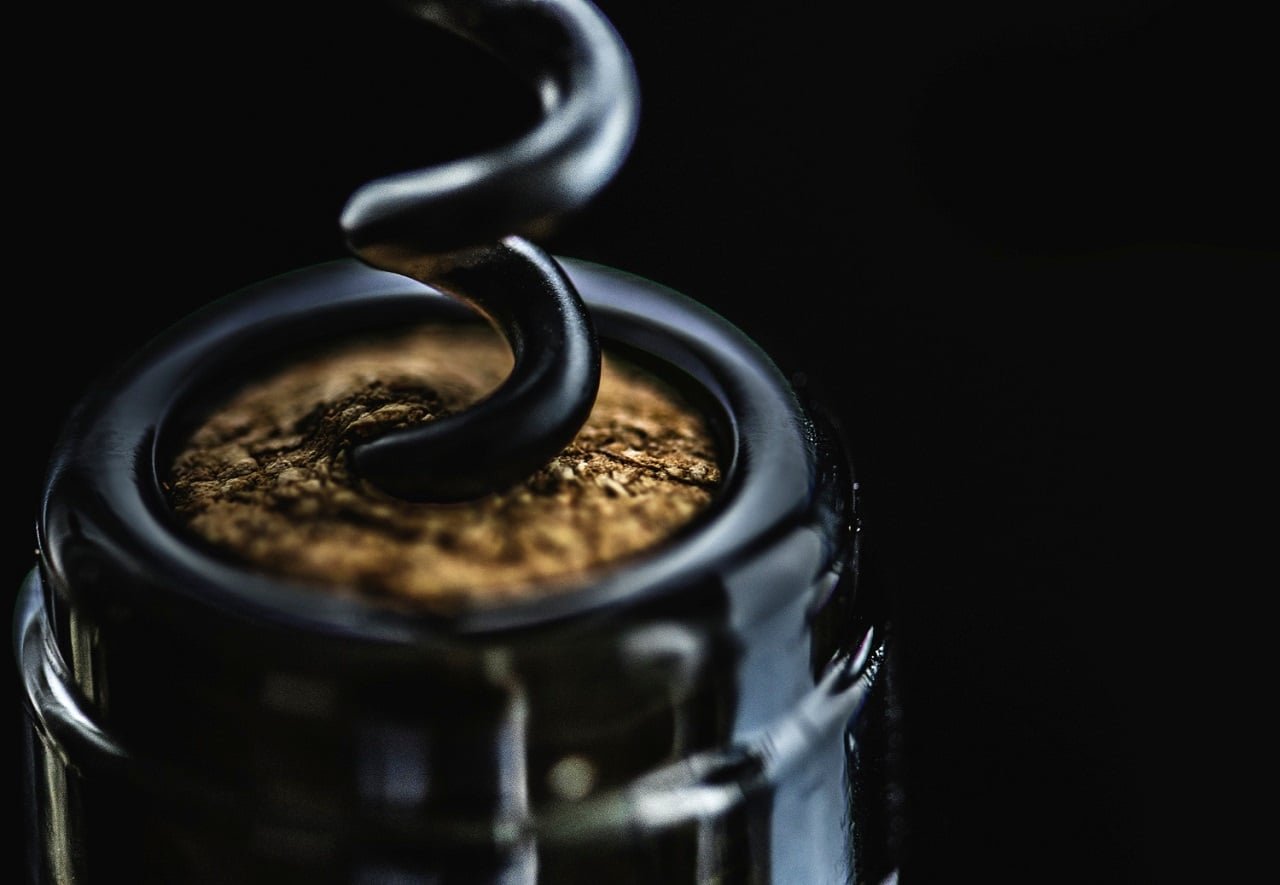 Un gros plan sur fond noir sur le goulot d'une bouteille de vin dans laquelle s'enfonce le bout d'un tire bouchon