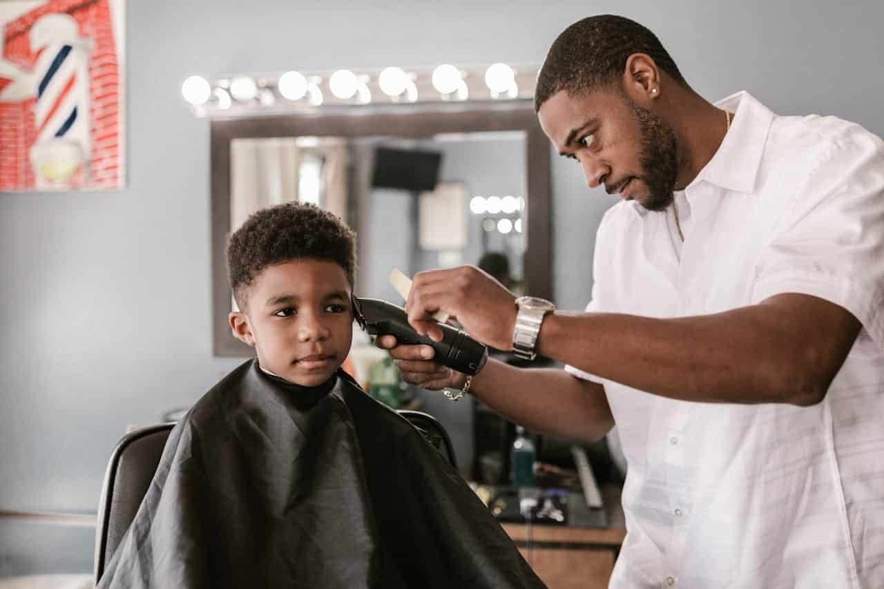 Un enfant chez le barber se faisant couper les cheveux avec une tondeuse à cheveux professionnelle