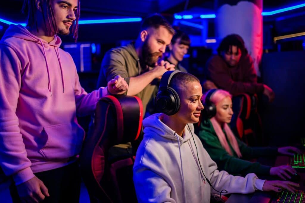 Gamer girls playing video game and competing while friends watching.