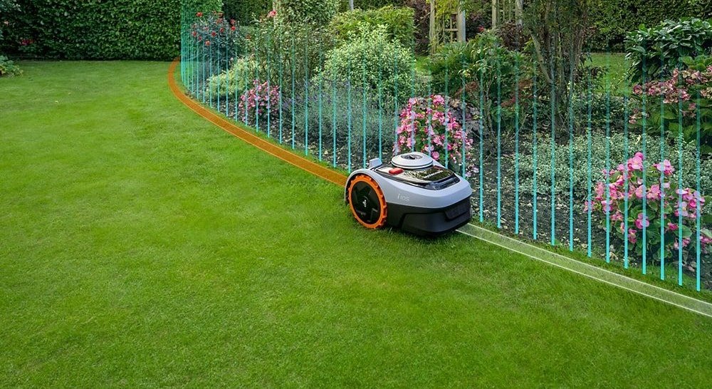 Le robot tondeuse Segway i105E en train de tondre une pelouse, longeant un massif de fleurs