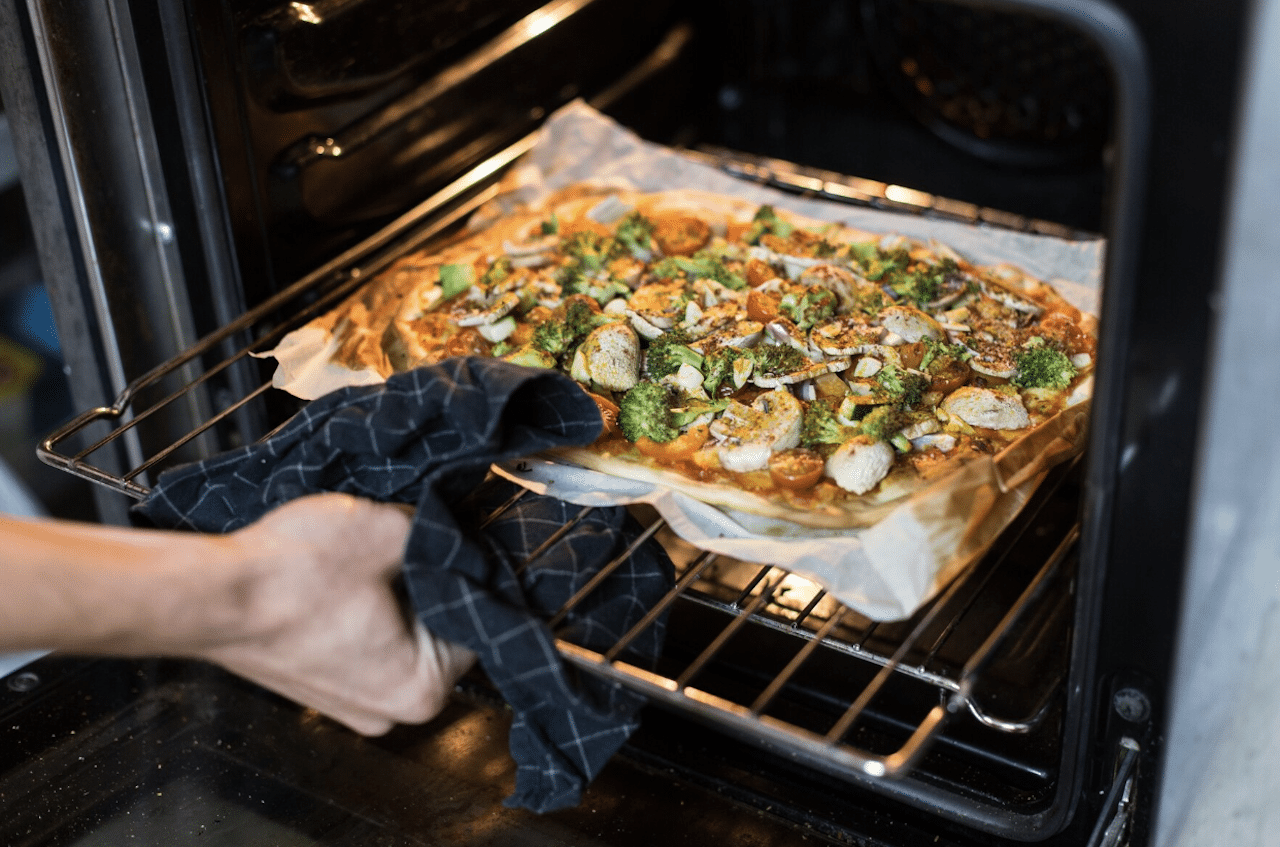 Une personne en train de sortir une pizza du four.