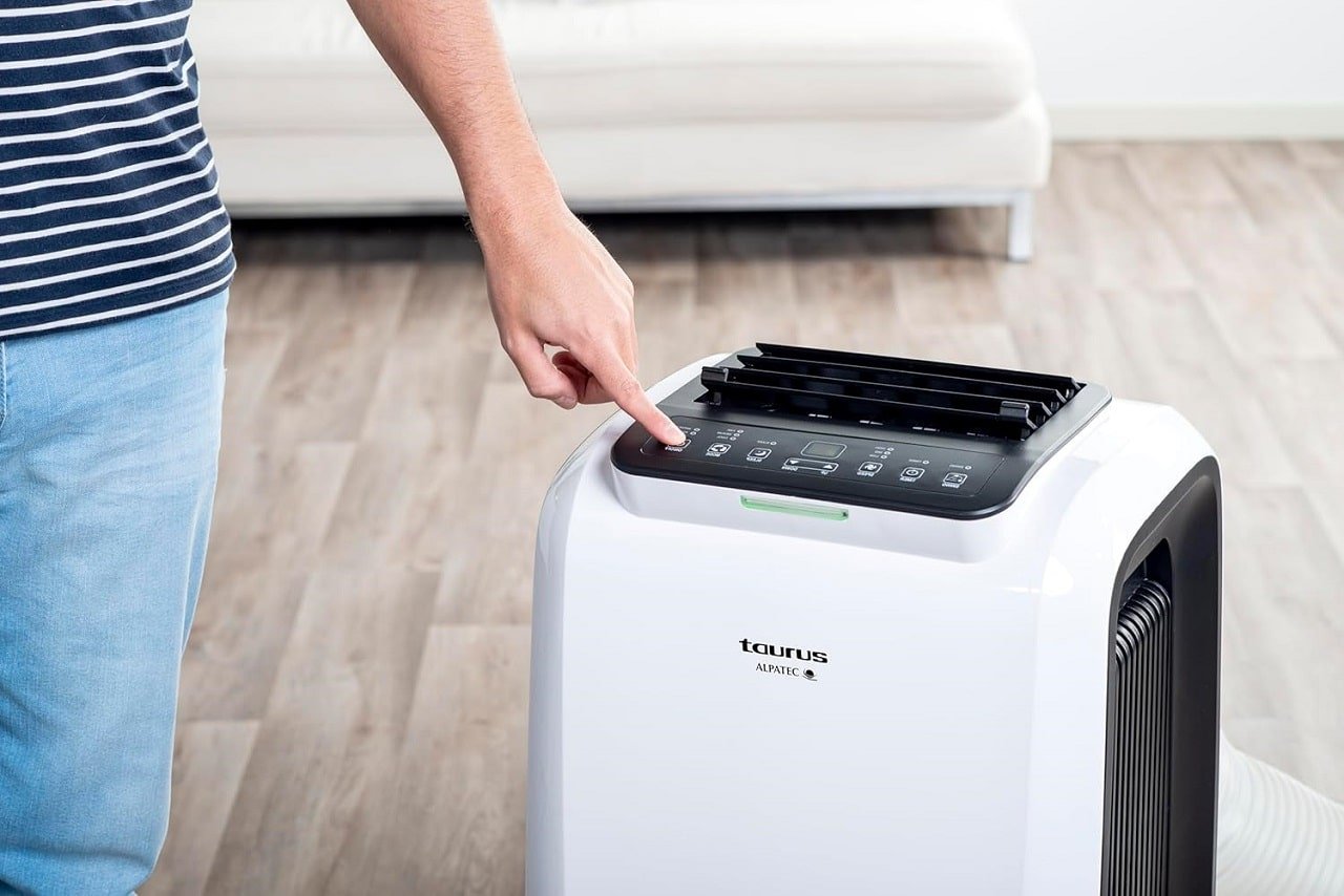 Un homme réglant la température d'un climatiseur mobile Taurus Alpatec