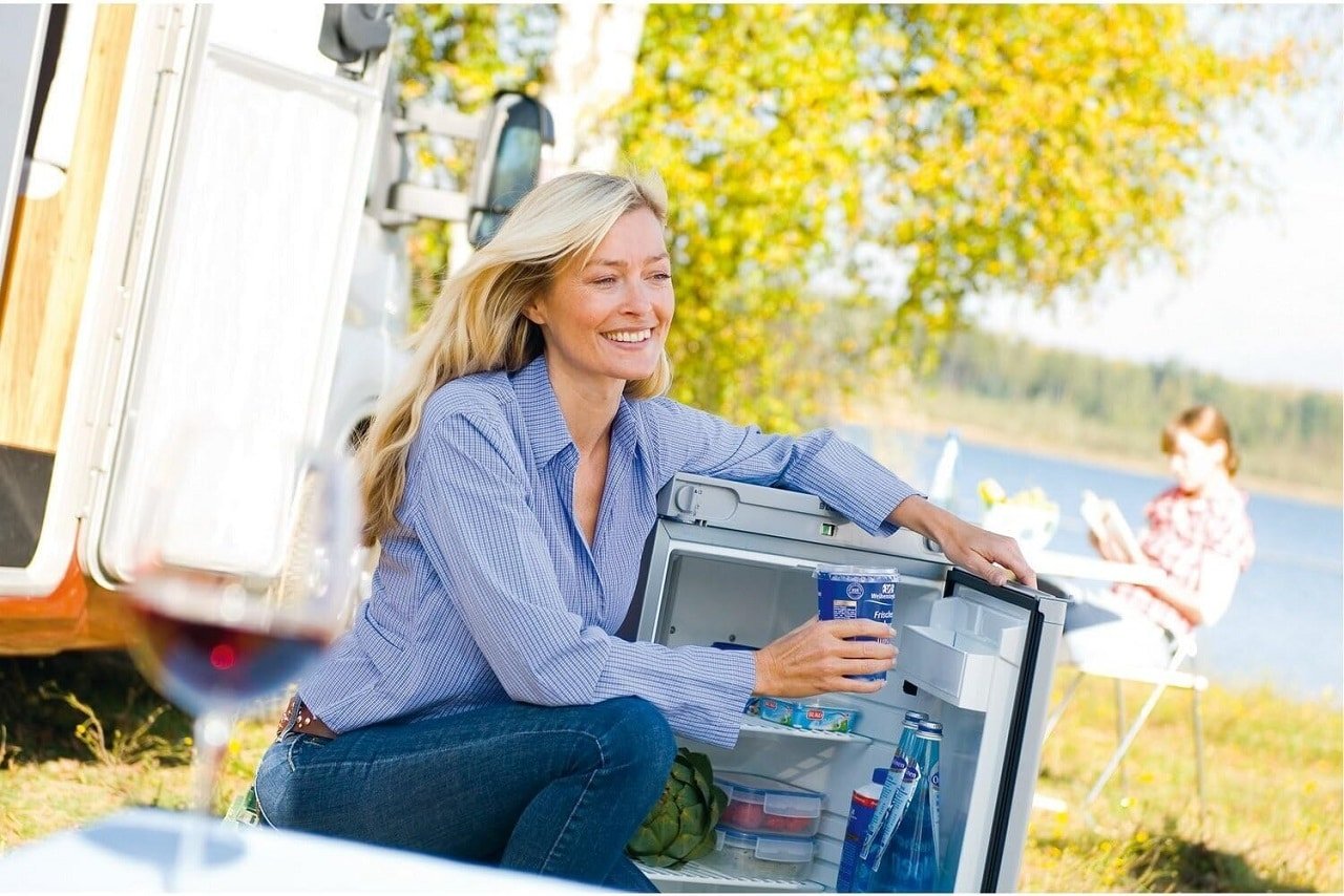 Une femme en camping profite d'un réfrigérateur mobile Dometic