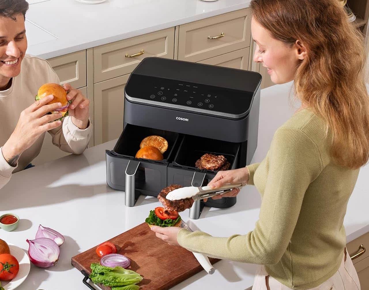 Un couple en train de préparer à manger à l'aide d'une friteuse sans huile de la marque Cosori.