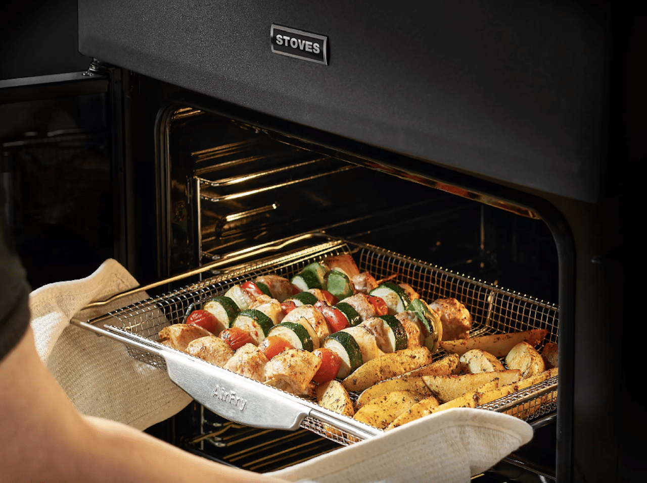 Une personne en train de sortir un plat d'un piano de cuisson de la marque Stoves.