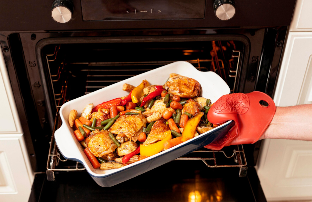 Un plat de légumes et de poulet qui sort du four.