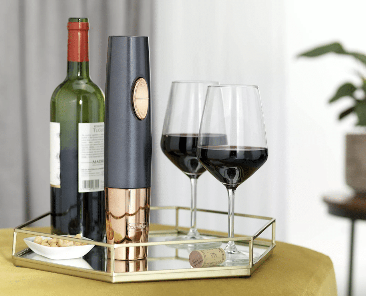 Un tire bouchon de la marque Cuisinart disposé à côté d'une bouteille de vin et deux verres à vin.