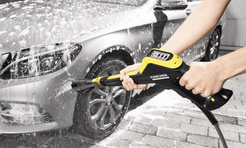 Une femme qui nettoie sa voiture à l'aide d'un nettoyeur haute pression de la marque Kärcher.