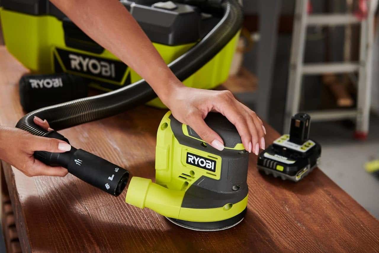 Un homme qui utilise une ponceuse excentrique de la marque Ryobi.