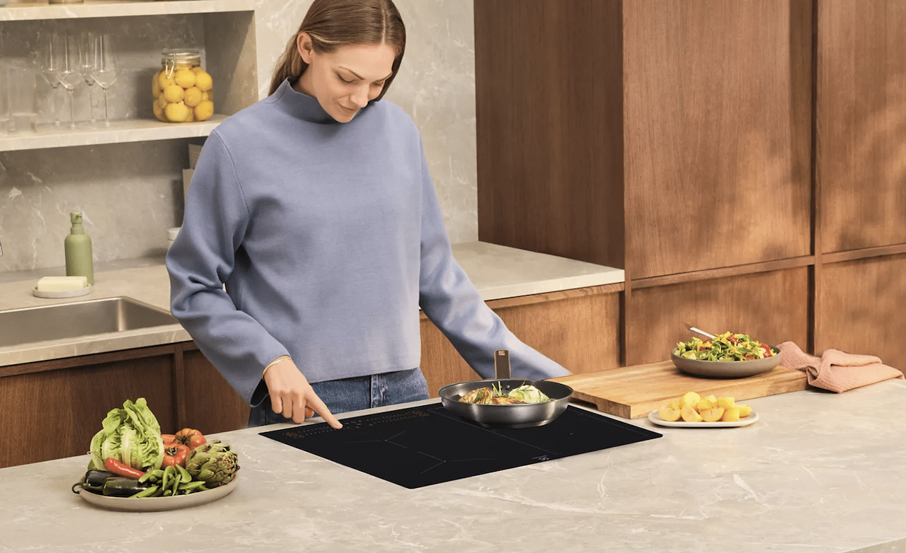 Une femme en train de cuisinier avec un plaque à induction.