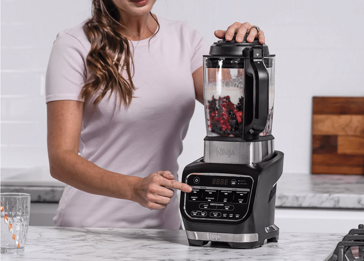 Une femme qui utilise un blender chauffant de la marque Ninja.