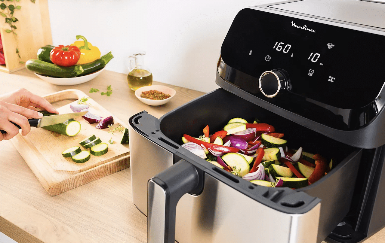 Une friteuse de la marque Philips avec des légumes dans le bac.