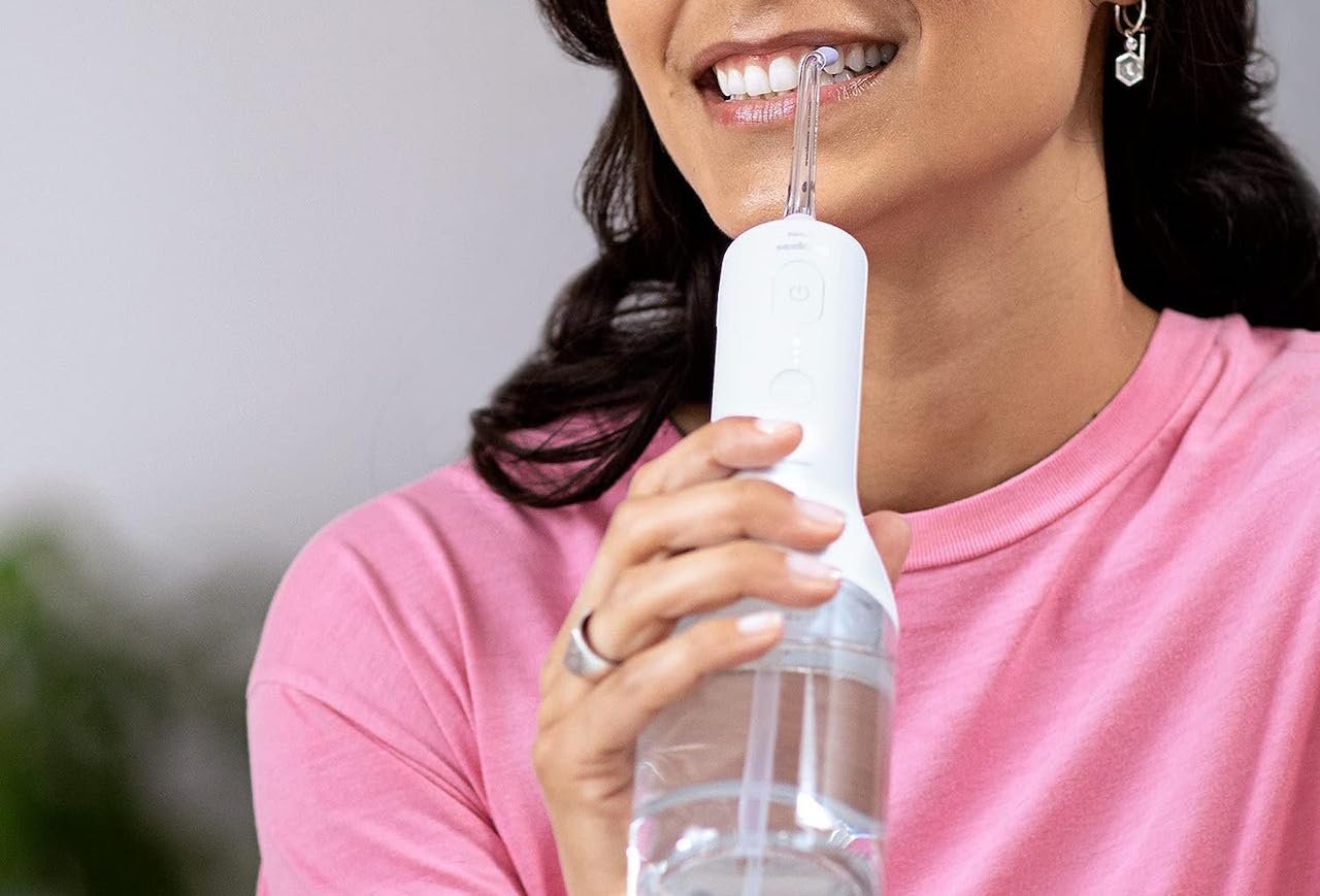 Une femme qui utilise un hydropulseur dentaire.