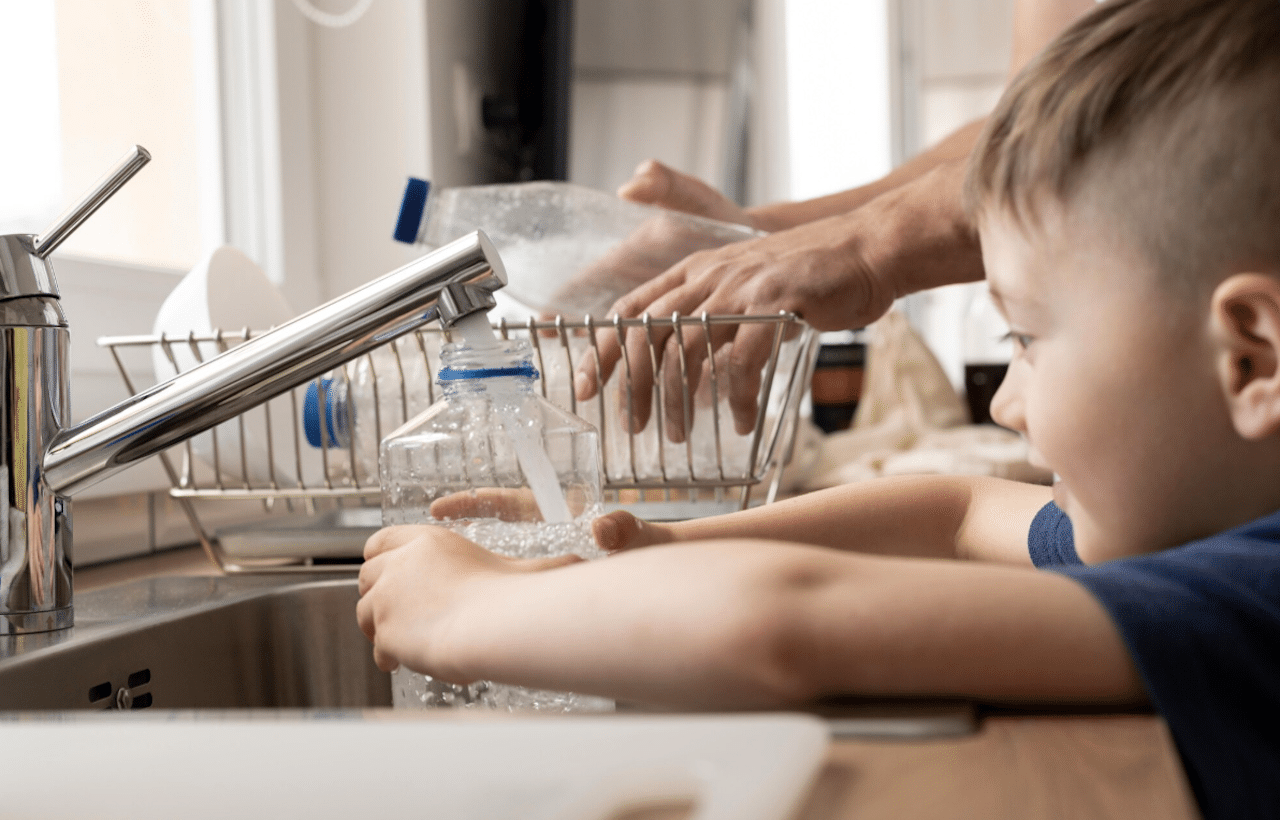 Une petit garçon qui se sert de l'eau du robinet.