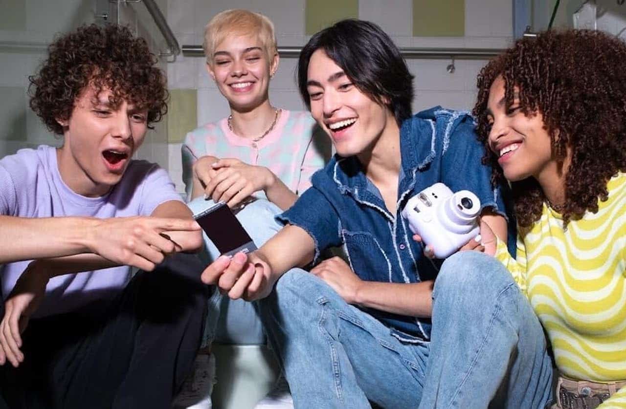 Quatre jeunes amis qui regardent une photo qu'ils ont prise avec un appareil photo instantané.