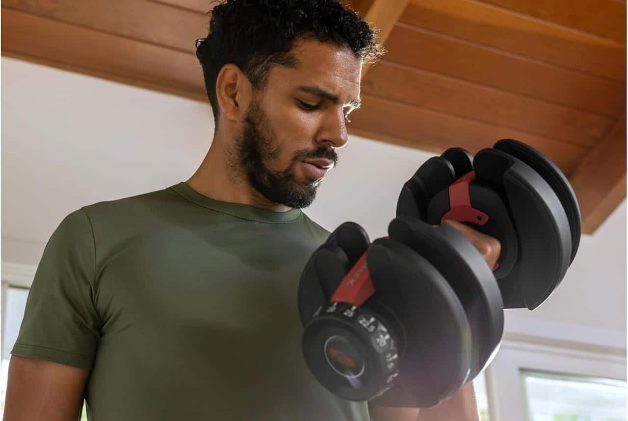 Une homme qui porte un haltère réglable.
