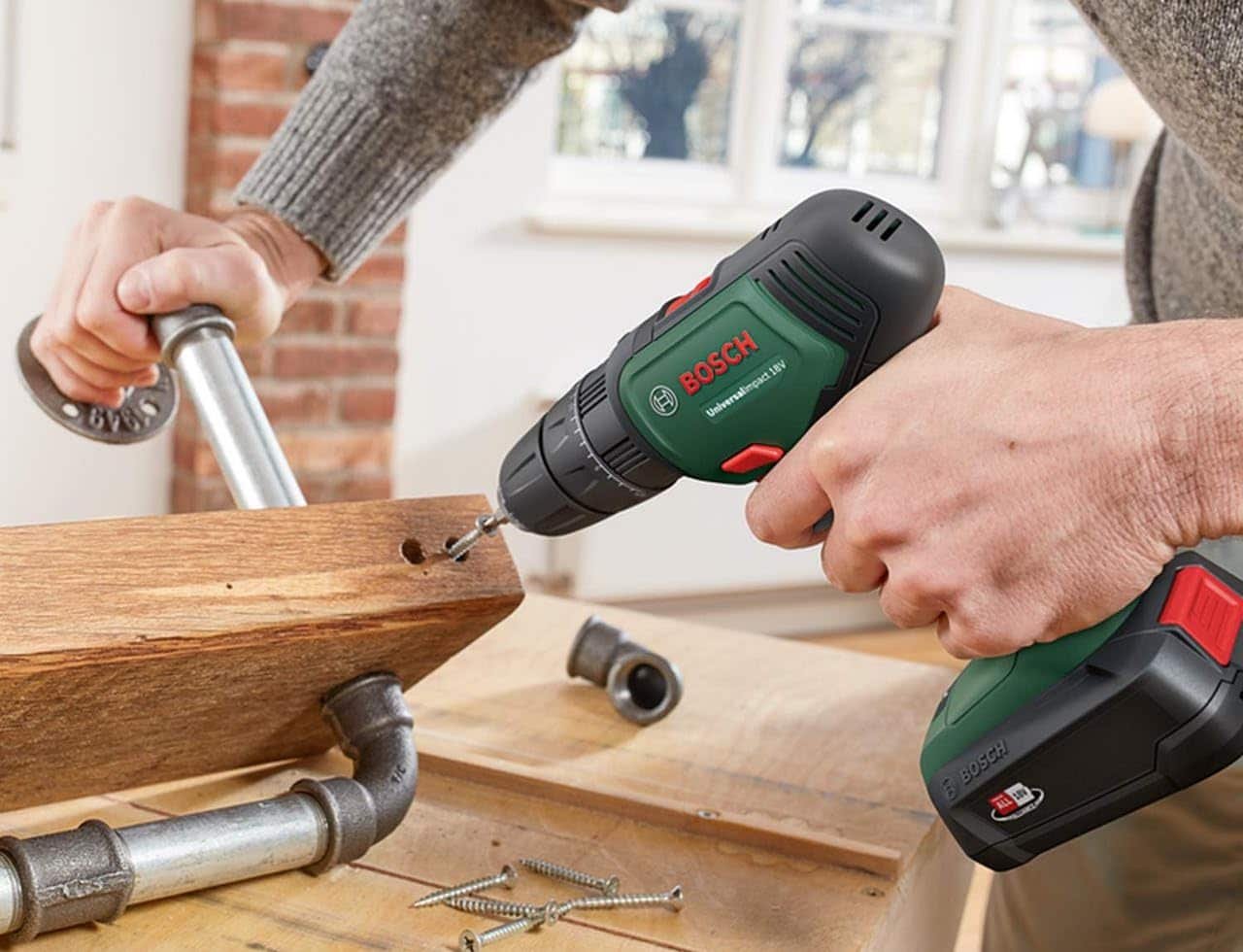 Un homme qui utilise une perceuse à percussion de la marque Bosch.