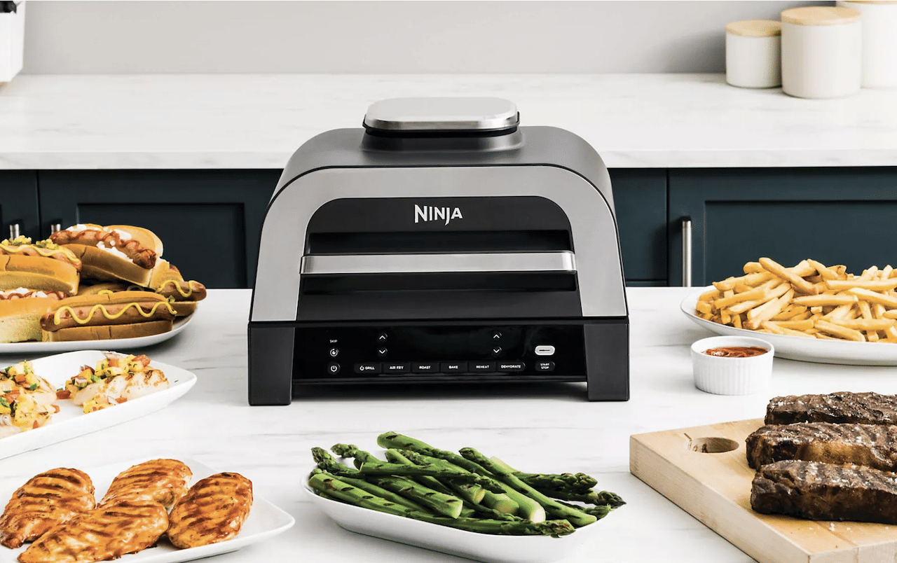 Un grill-viande de la marque Ninja entouré de plats préparés au grill-viande. 