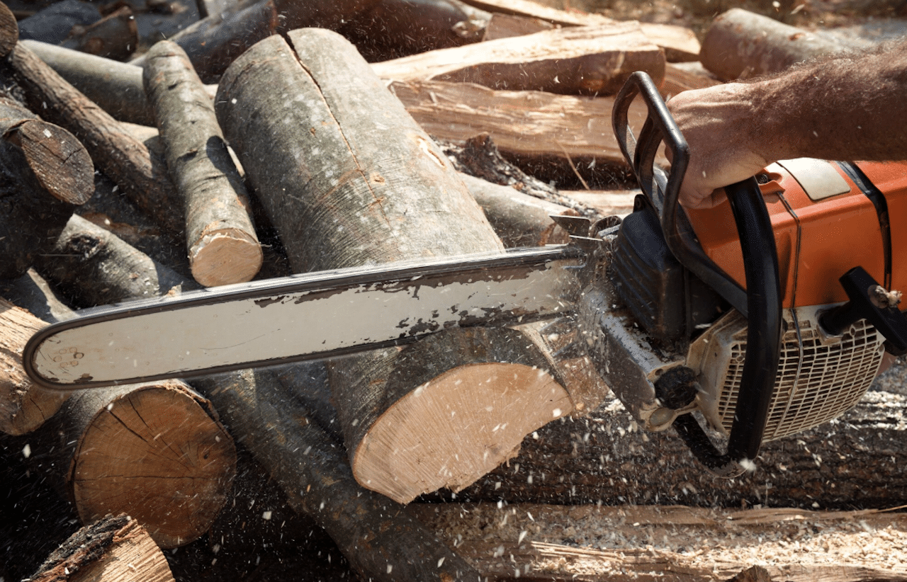 Une personne qui utilise une tronçonneuse pour couper un tronc d'arbre.