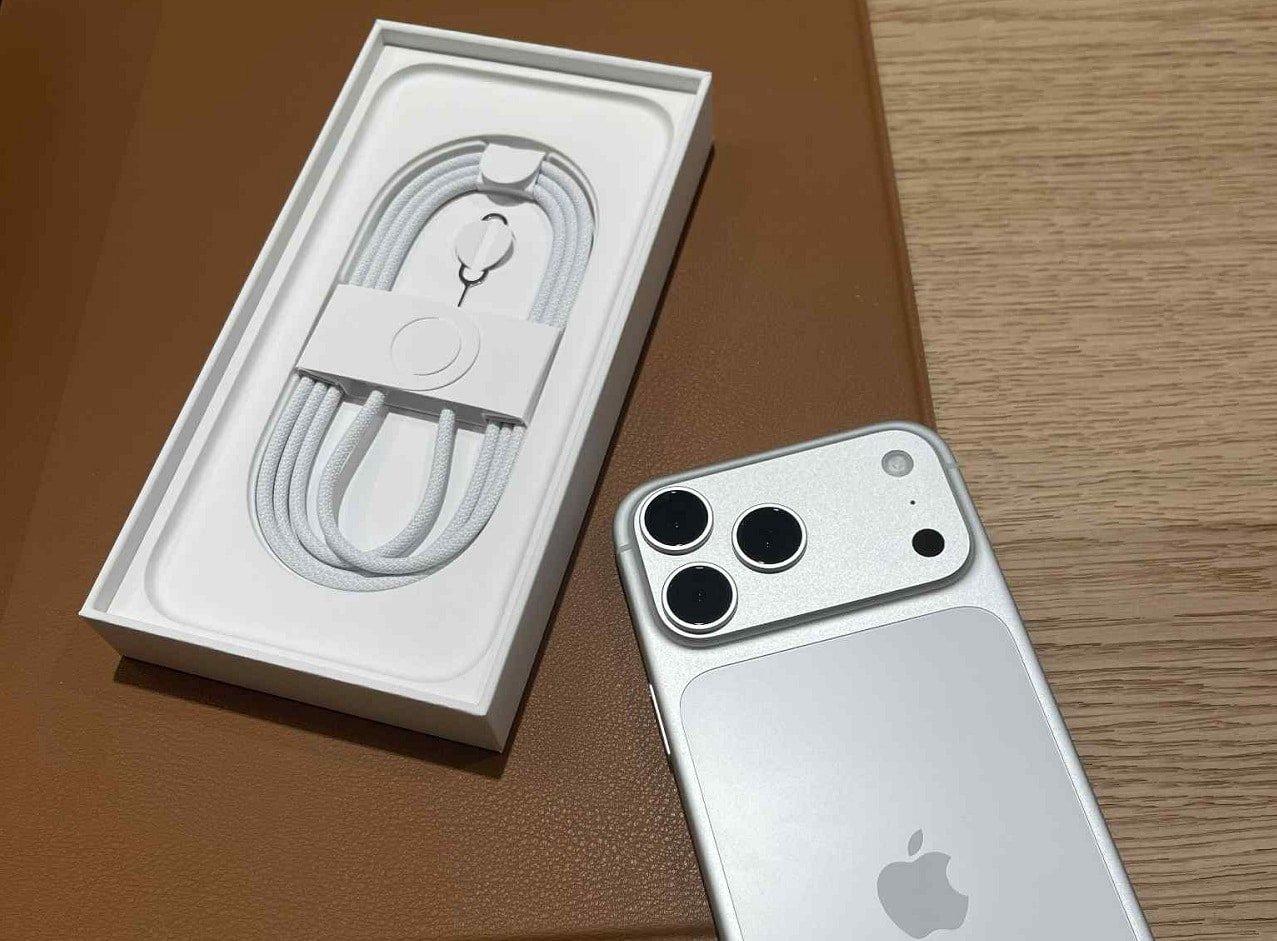 iPhone 17 Pro MAx posé sur une table face arrière visible à coté de sa boite ouverte où apparait le câble de recharge