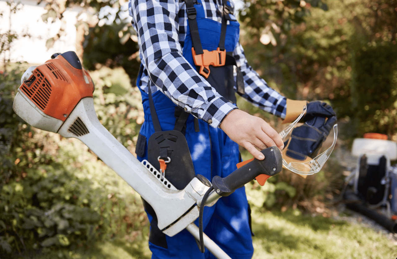 Un homme qui utilise une débroussailleuse dans son jardin.